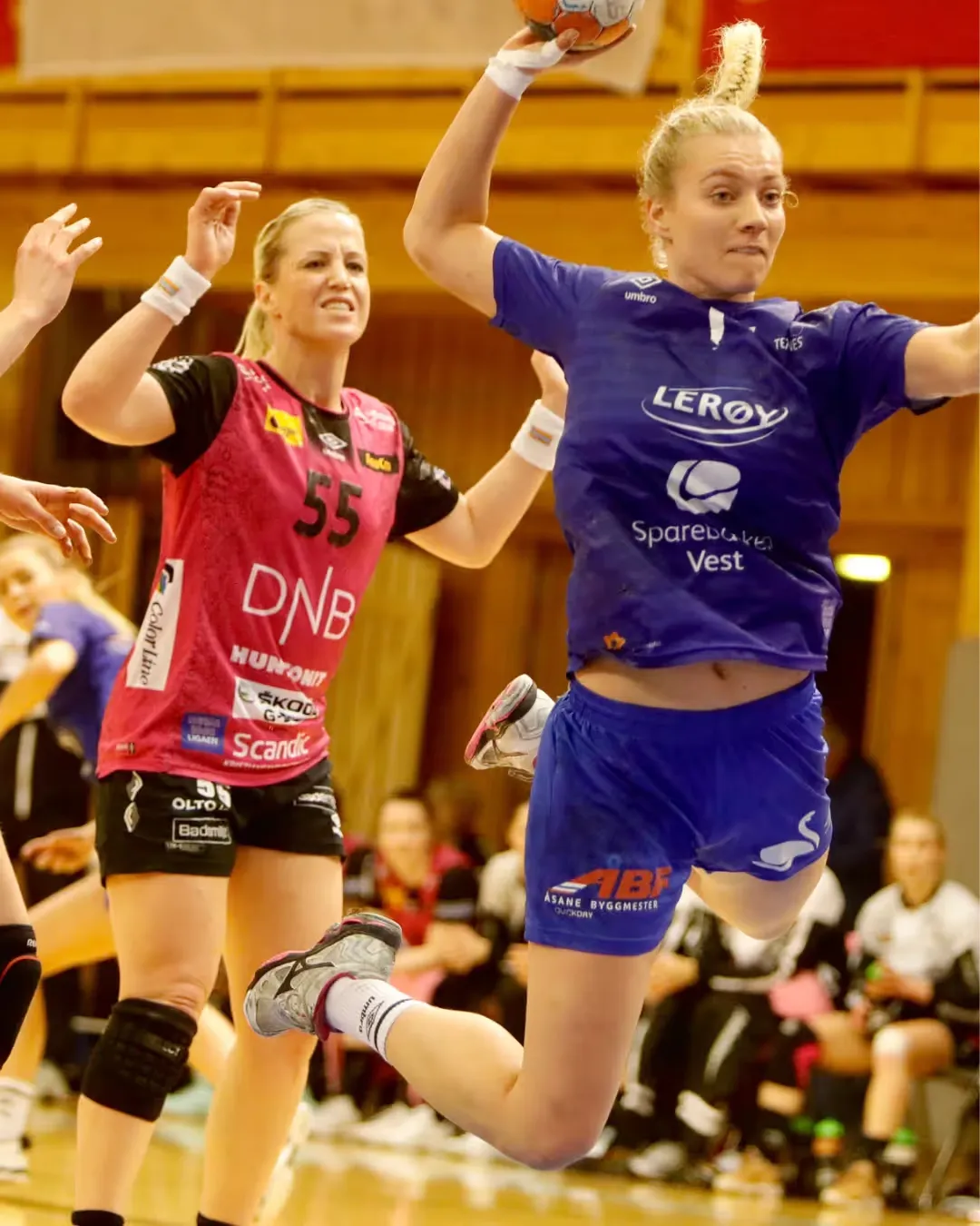 Håndballspiller i blå drakt i hopp med ballen mot mål